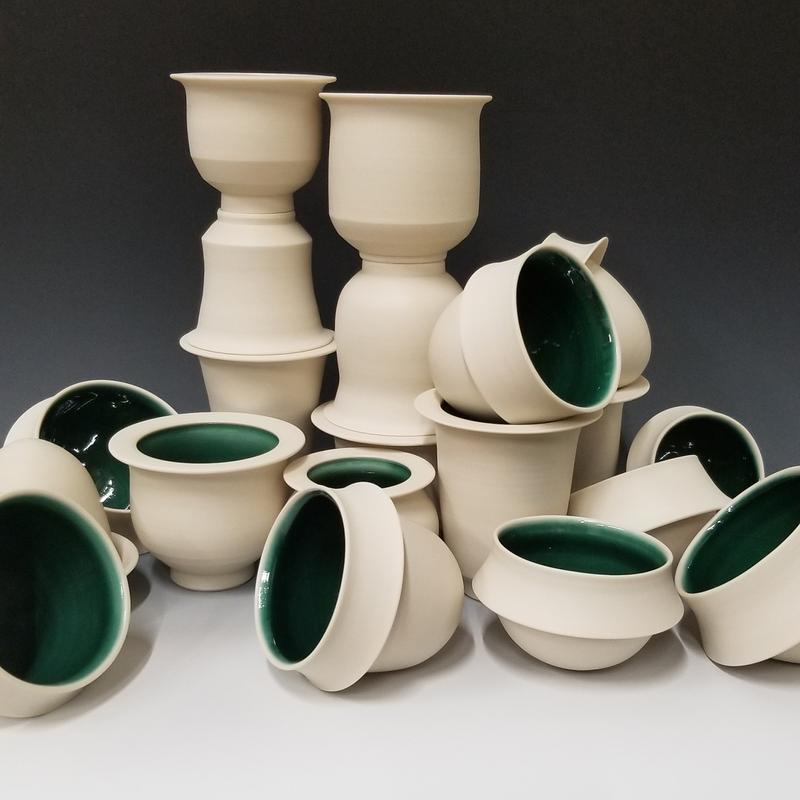 White porcelain cups with a bright green inside stacked on each other to form a random pile.